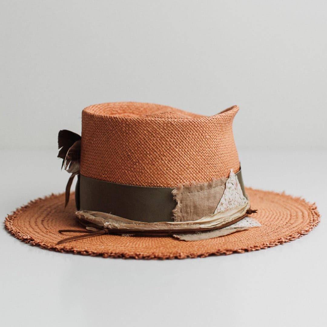 Back right angle of the Nim Panama biscuit Panama hat by PHYLLi Designs featuring floral and linen patches with tan suede string and sari silk trimming.