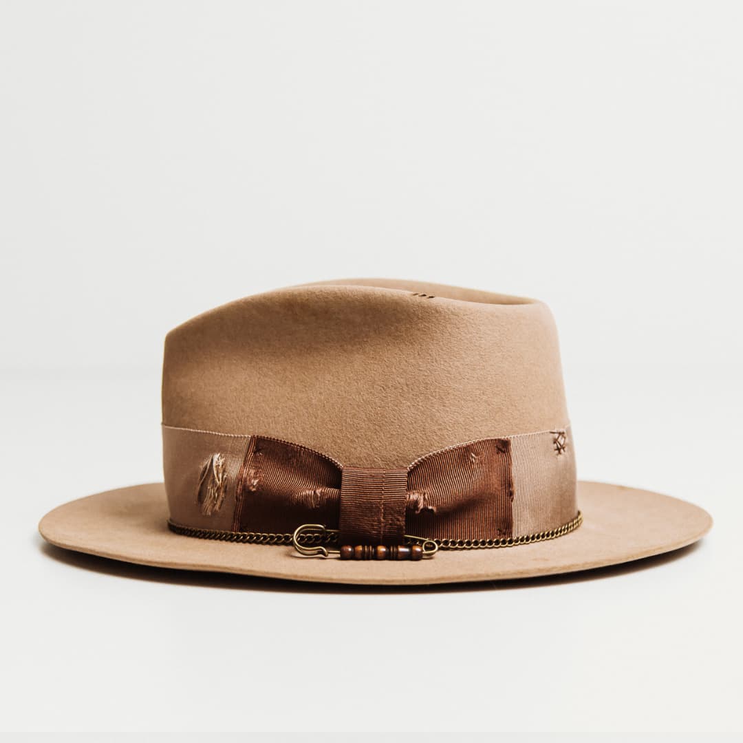 Left side view of the Normie sahara felt hat by PHYLLi Designs with distressed taupe grosgrain band, bronze crown chain and chocolate stitching detail.