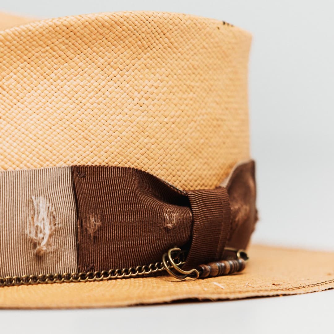 Detail of Normie Panama showing chocolate grosgrain bow, bronze hat pin with bone bead and crown chain.