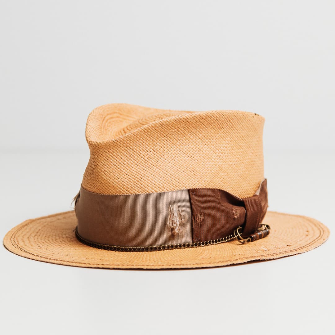 Normie Panama hat showing distressed Taupe grosgrain band, Chocolate bow and bronze hat pin with bone bead.