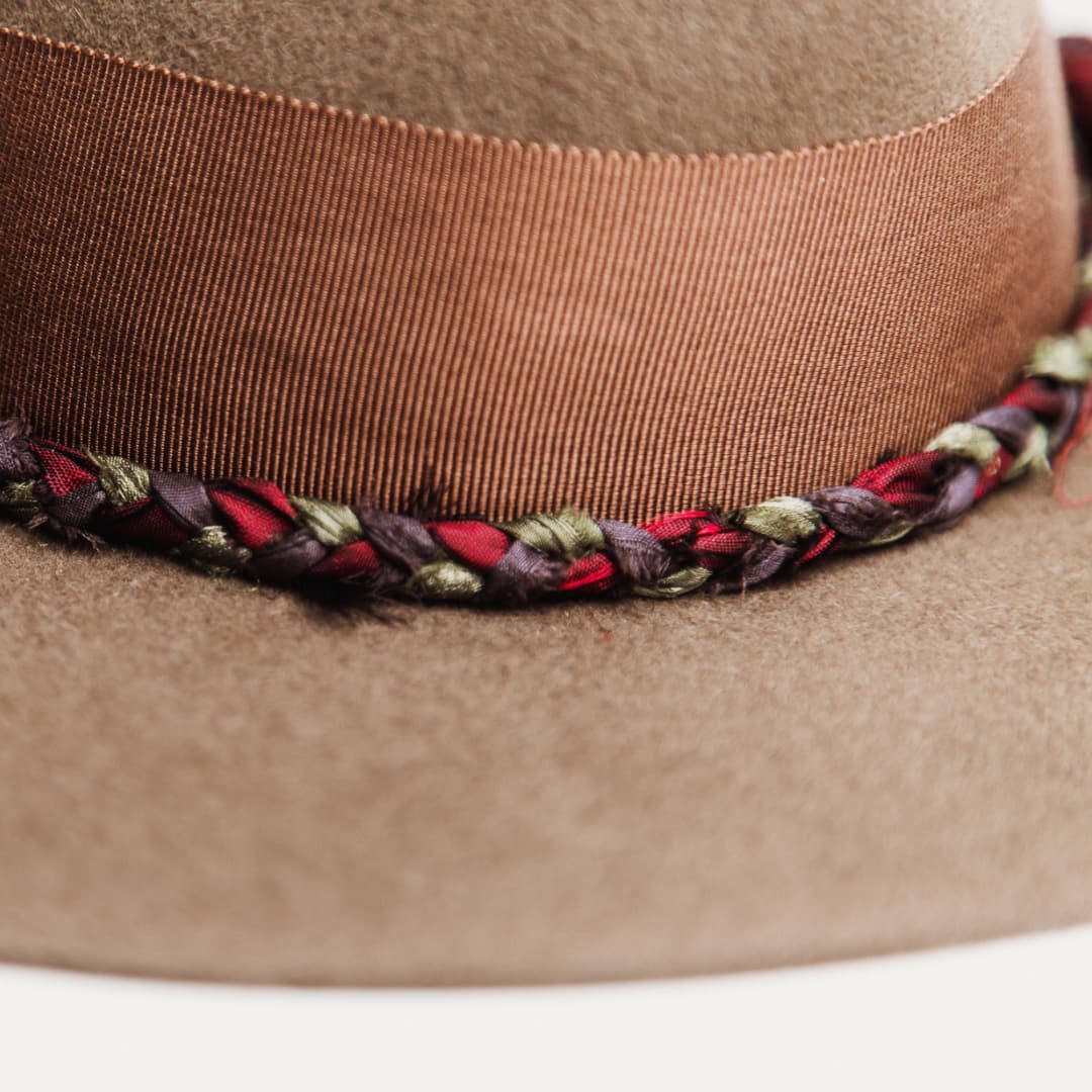 Close up detail of the Olive Enchanted felt hat showing plaited sari silk trimming in burgundy, green and purple.