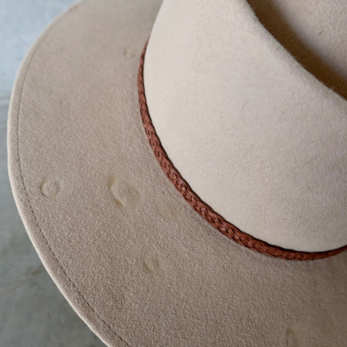 Close up detail of the Paisley felt hat showing distressed felt brim with single brim stitch in sand.
