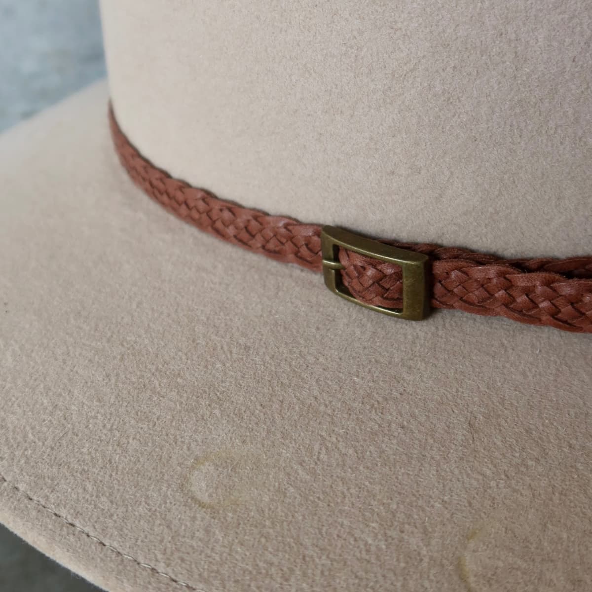 Close up detail of the Paisley felt hat showing eight strand plaited leather hat band with bronze buckle.