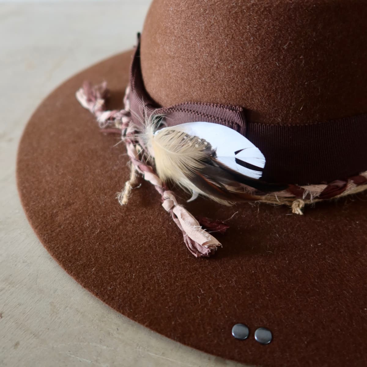 Close up detail of the Palmer Limited Edition felt hat showing gunmetal press studs on the felt brim.