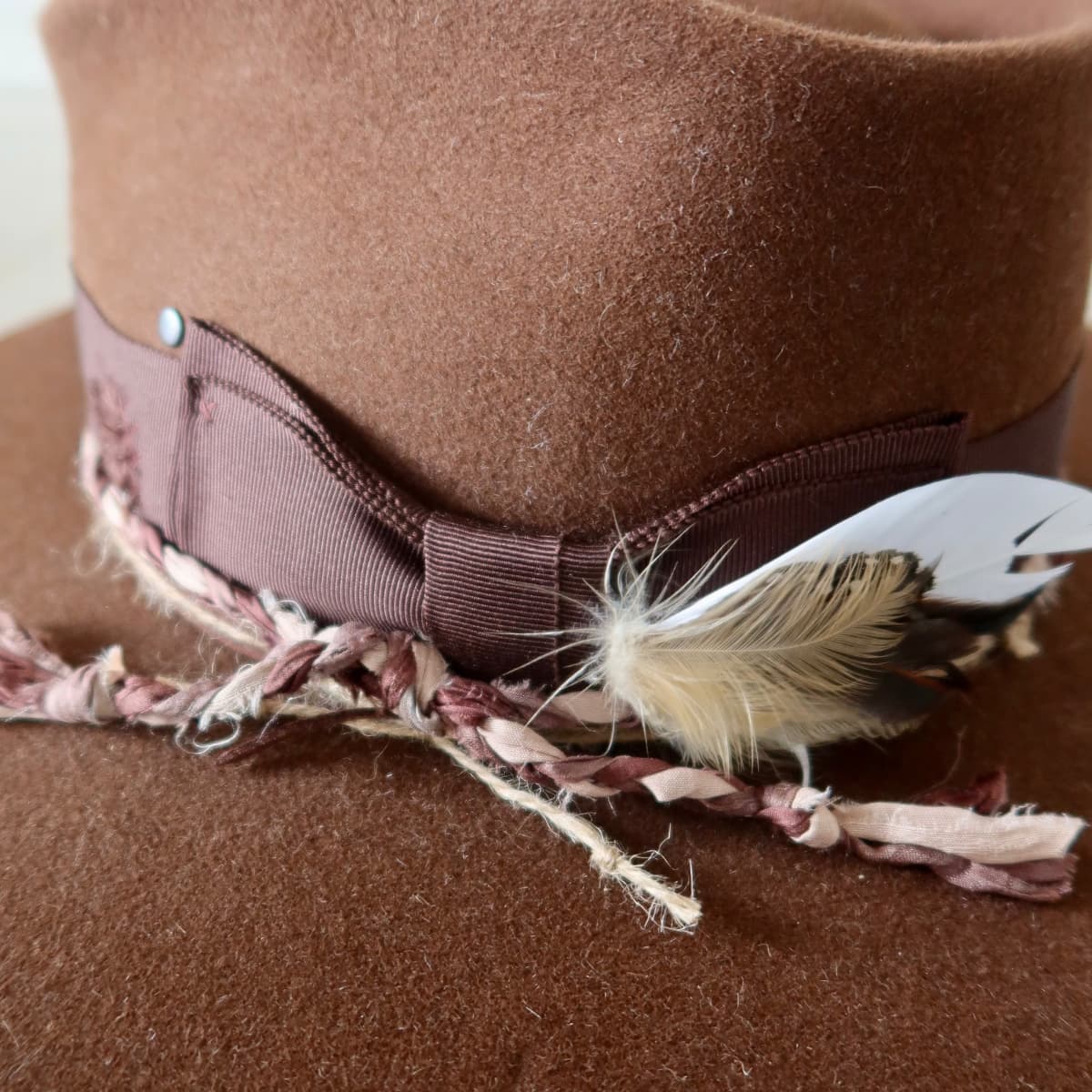 Close up detail of the Palmer Limited Edition felt hat showing fallen feather bunch and plaited sari silk trim.