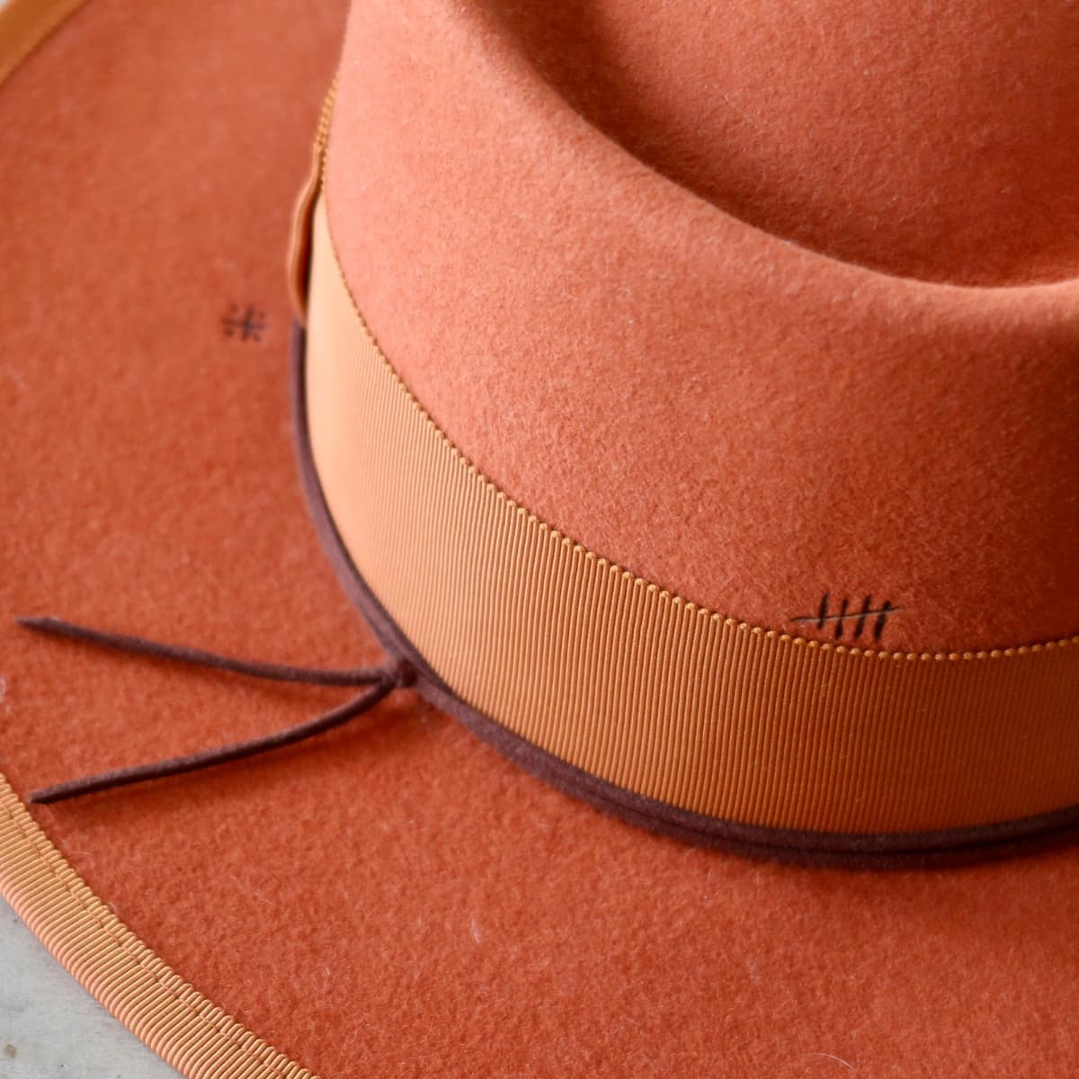 Close up detail of the Patrick felt hat showing burnt branded pattern on distressed spiced pumpkin felt.