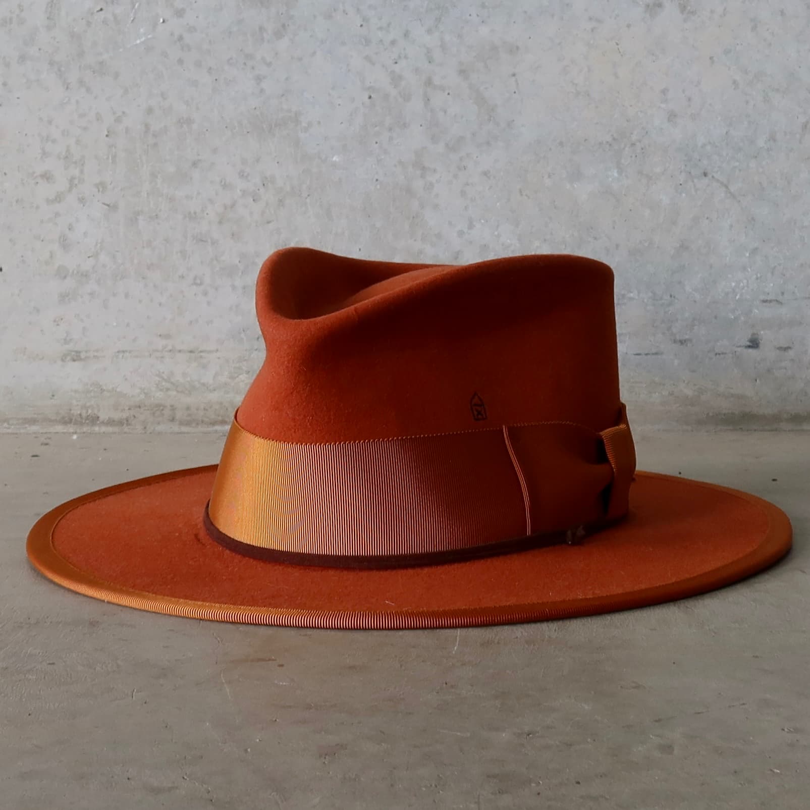 Front left angle of the Patrick spiced pumpkin felt hat by PHYLLi Designs with rust grosgrain bow band and chocolate suede string.