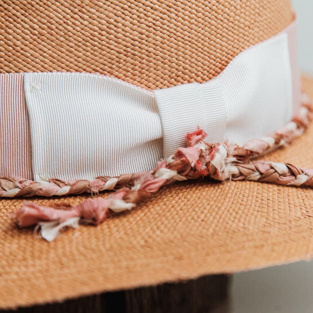 Close up detail of the Peach Panama hat showing plaited sari silk trimming in pink, bronze and ivory against handwoven toquilla straw.