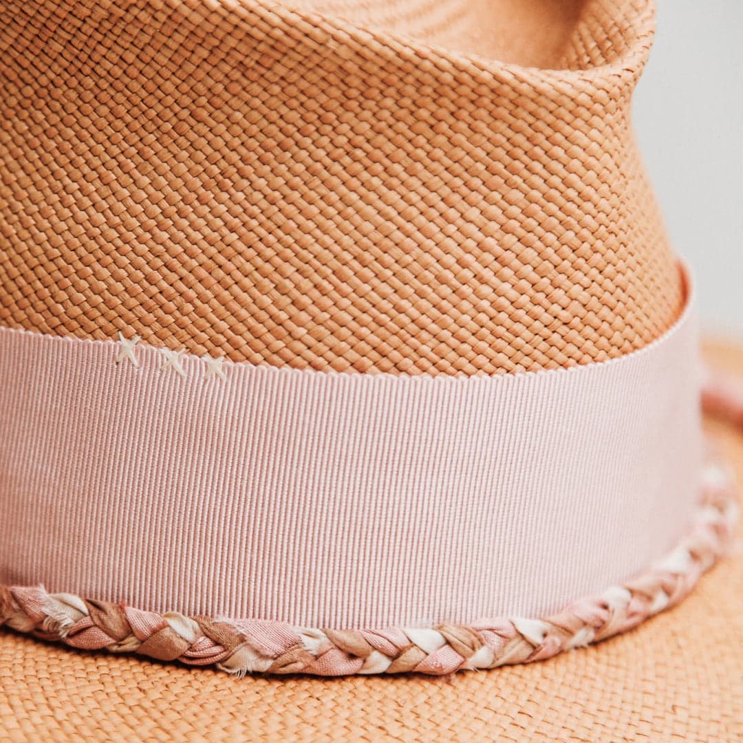 Close up detail of the Peach Panama hat showing hand-stitched ivory crosses on the floss pink grosgrain band.