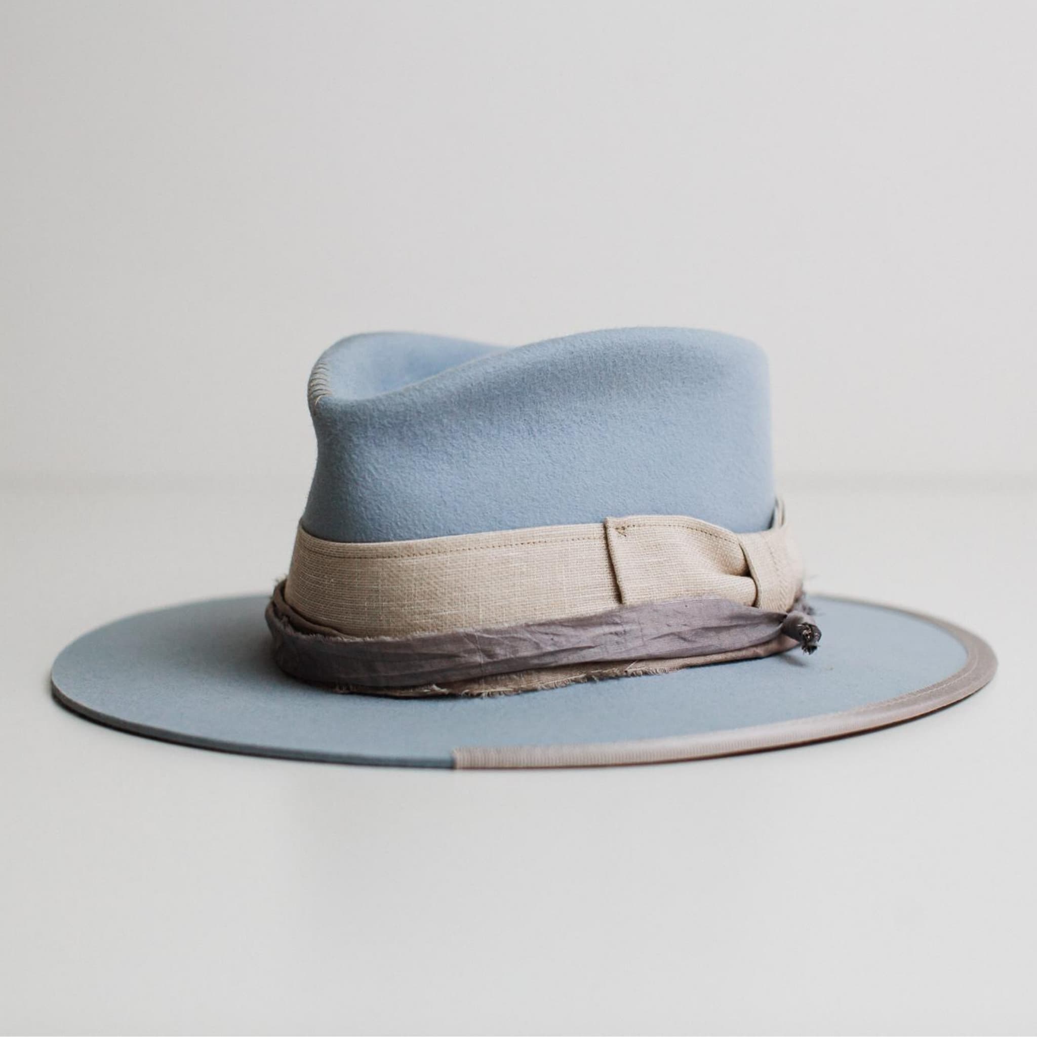 Front left angle of Perfect Storm crystal blue rabbit felt hat by PHYLLi Designs with linen bow band, sari silk trim and silver grosgrain brim trim.