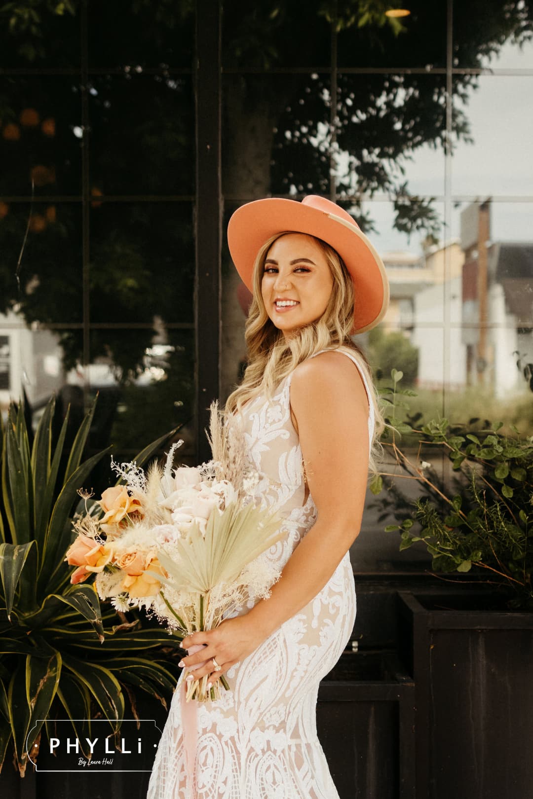 Bride wearing a peach felt wedding hat by PHYLLi Designs with a fitted lace wedding dress and bouquet.