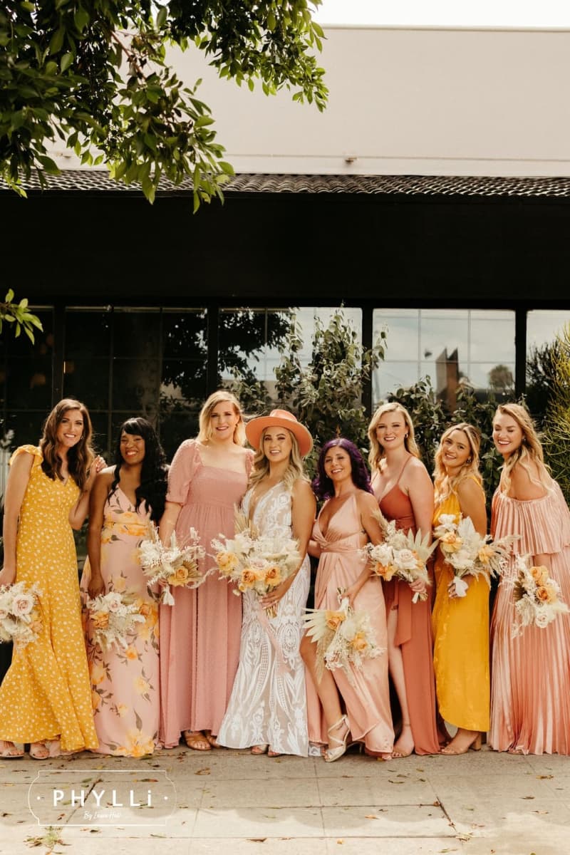 Bride with bridesmaids in pastel dresses featuring a felt wedding hat by PHYLLi Designs for a modern bridal party look.