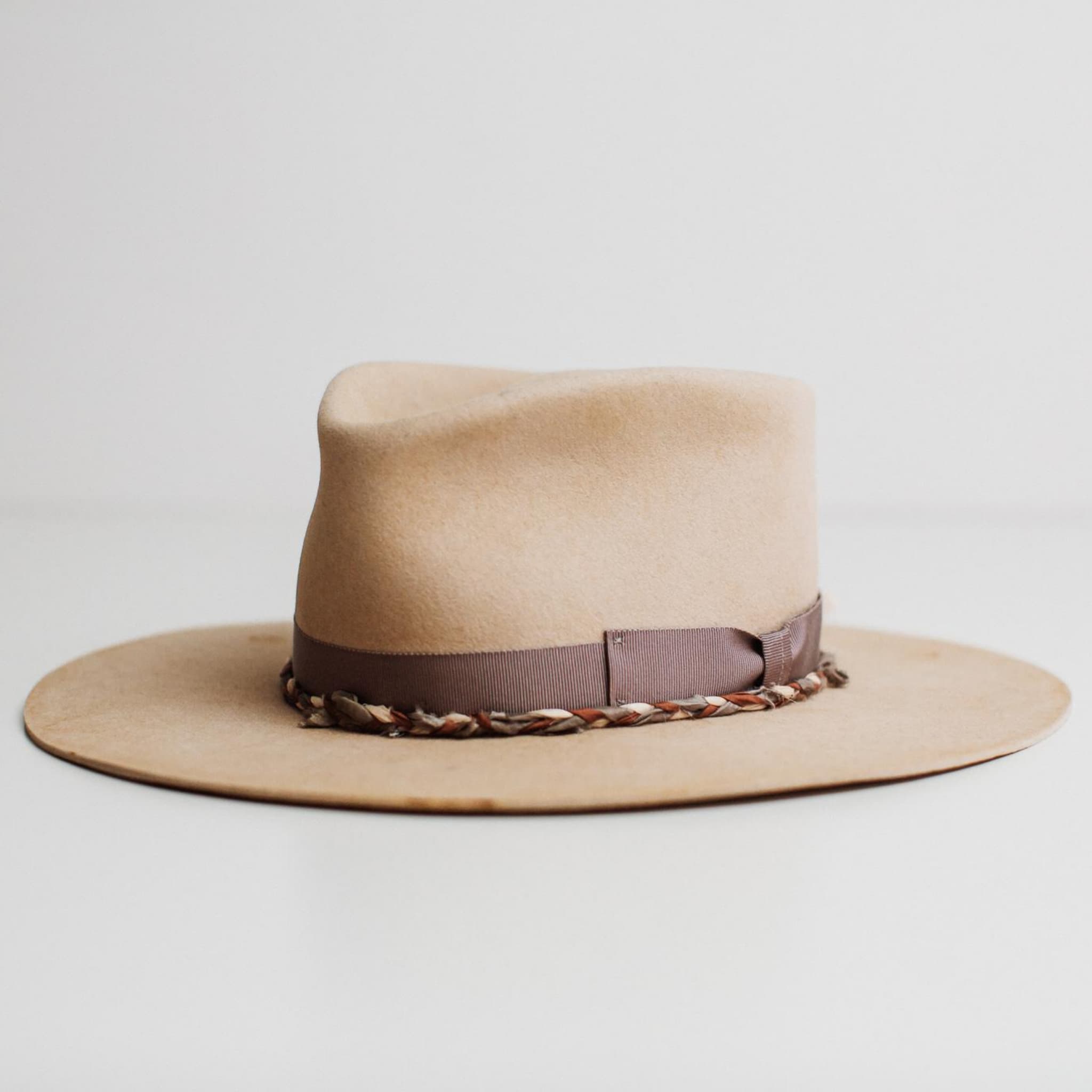 Front left angle of Plum Twist beige rabbit felt hat by PHYLLi Designs with mauve grosgrain bow band and plaited sari silk trim in mauve, ivory and plum.