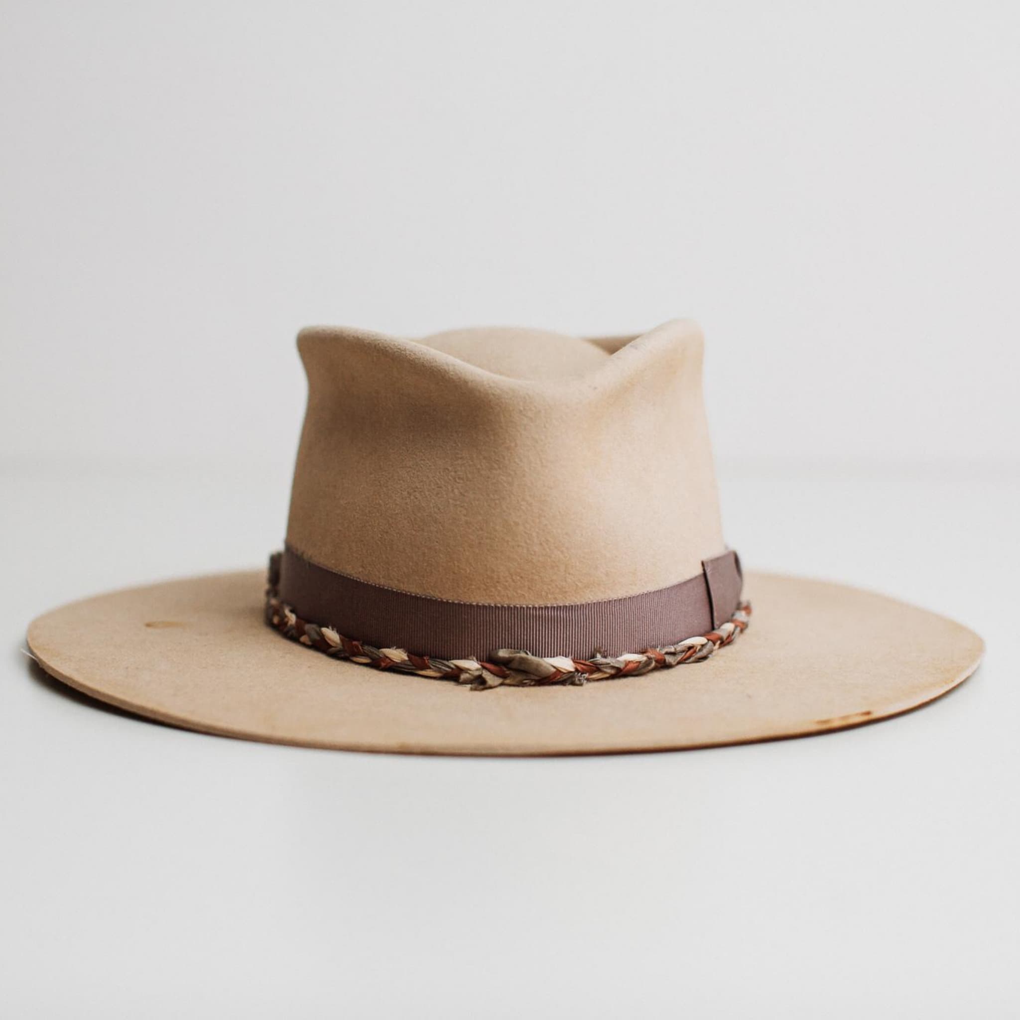 Front view of Plum Twist beige distressed premium felt hat by PHYLLi Designs with mauve vintage grosgrain bow band and plaited sari silk trim on white background.