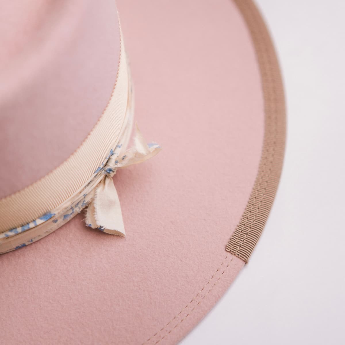 Close up detail of the Posie felt hat showing cream and blue patterned sari silk trimming beneath the grosgrain band.