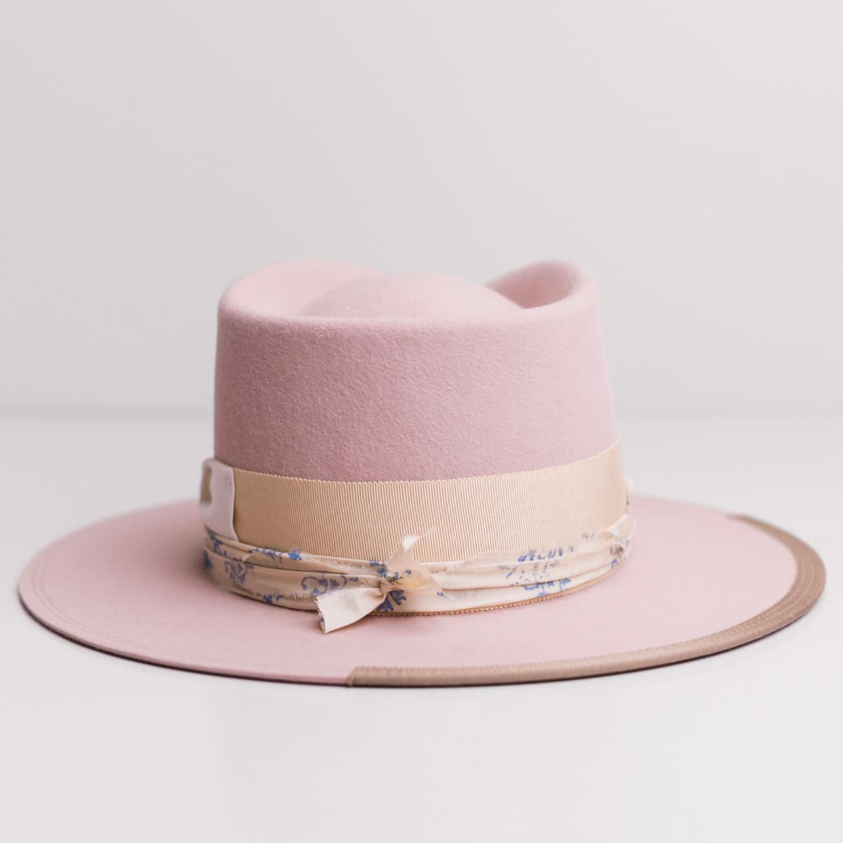 Back view of the Posie Baby Pink felt hat by PHYLLi Designs featuring sand grosgrain band with ivory bow.