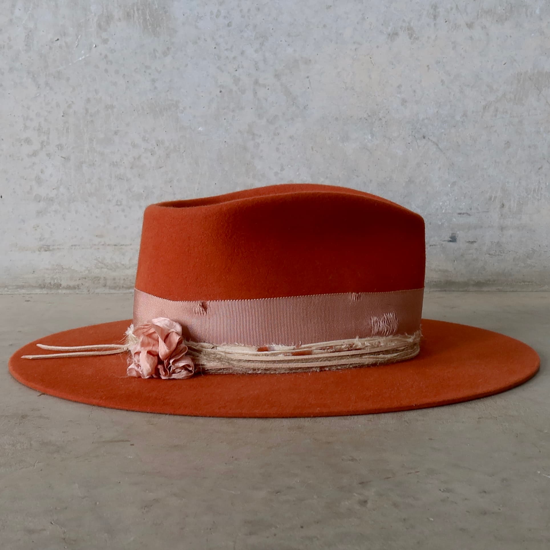 Right side view of the spiced pumpkin felt hat Pumpkin Bloom by PHYLLi Designs featuring sari silk lapel blooms, distressed dirty rose grosgrain bow band and layered twine wraps.