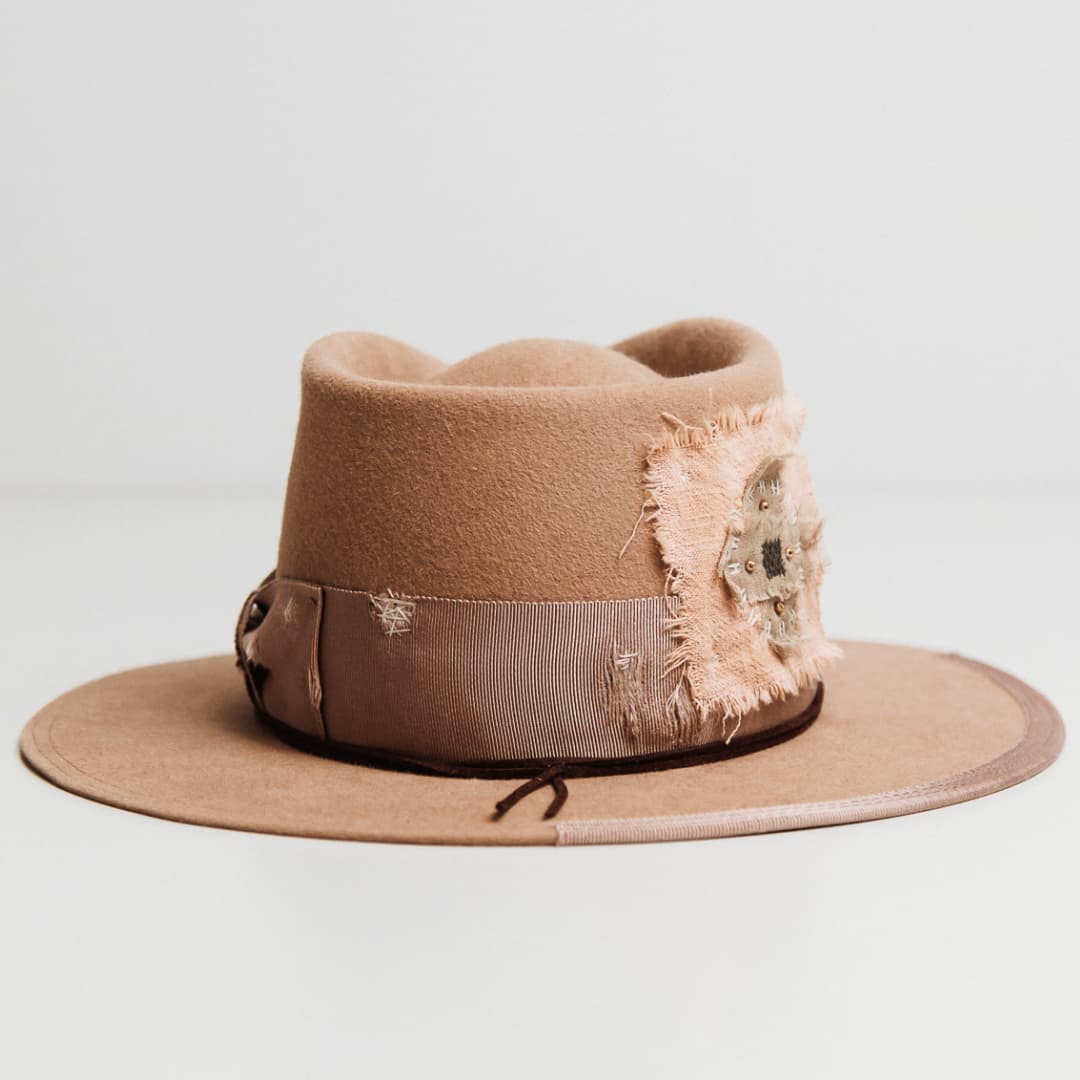 Back view of the Reiko camel felt hat by PHYLLi Designs featuring distressed ivory darned patches on the grosgrain band and pink linen cross patch.