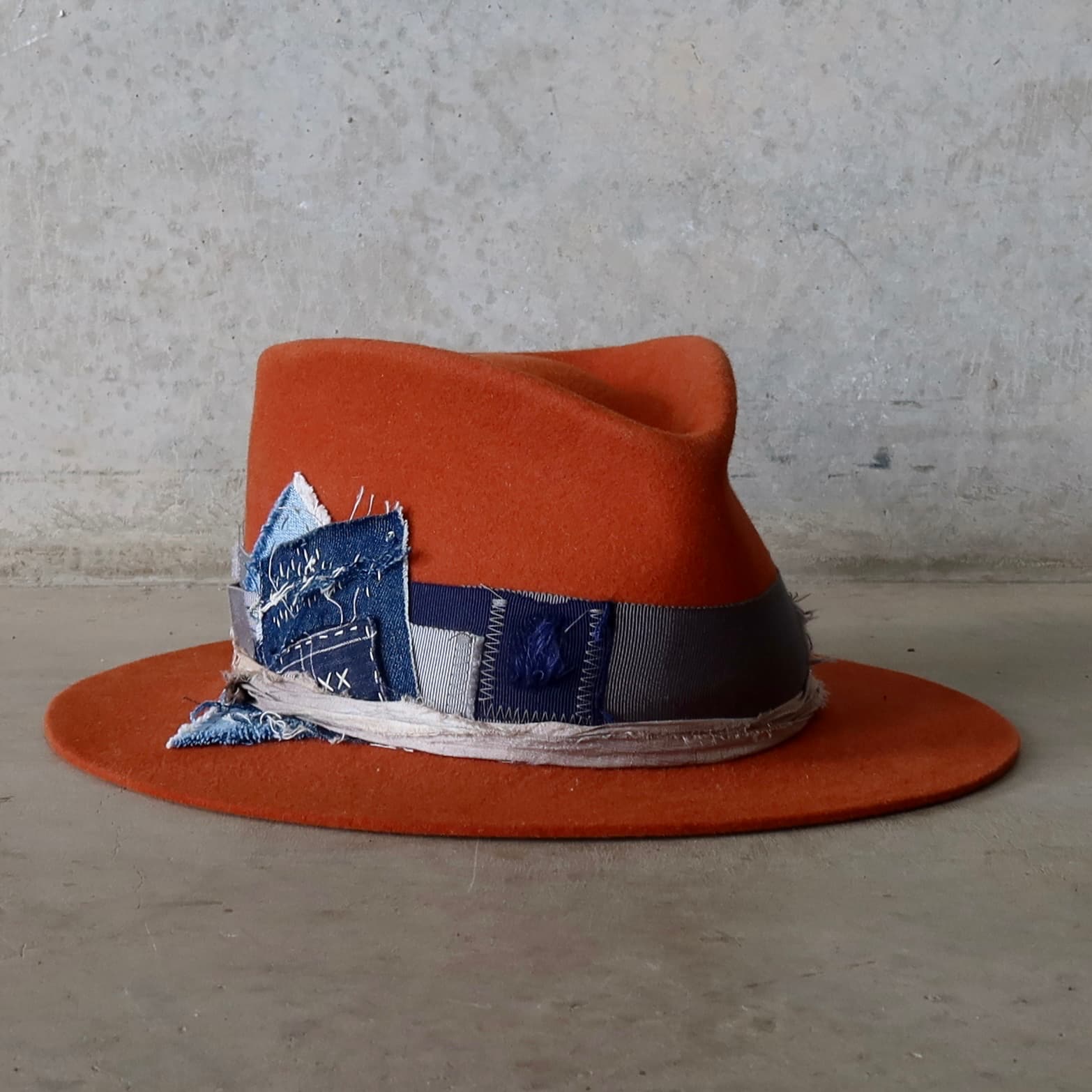 Front right angle of the Road Less Travelled spiced pumpkin felt hat by PHYLLi Designs with distressed grosgrain bow and sari silk trim.