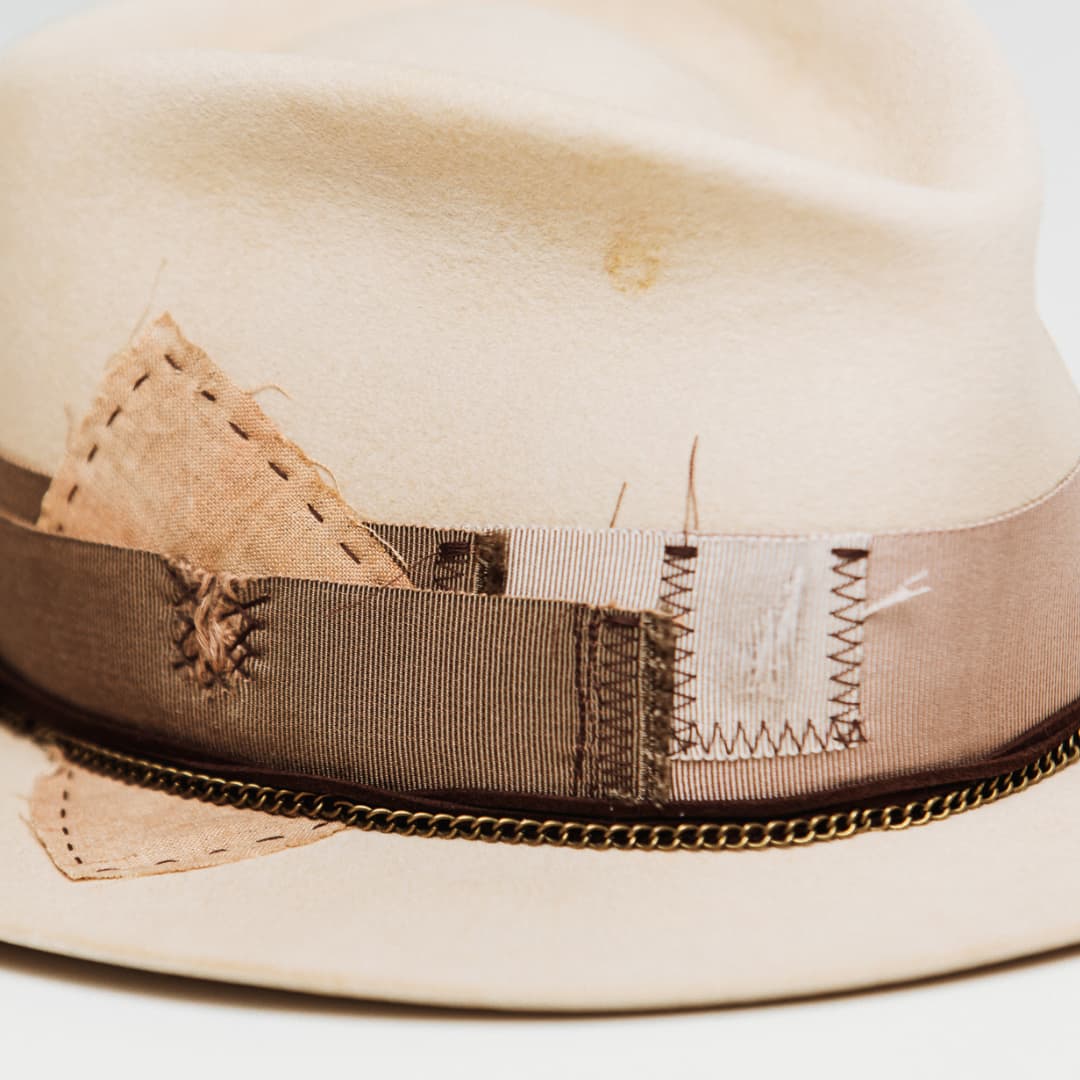 Close up detail of the Roadie felt hat showing patchwork fabric panels stitched into the grosgrain band.