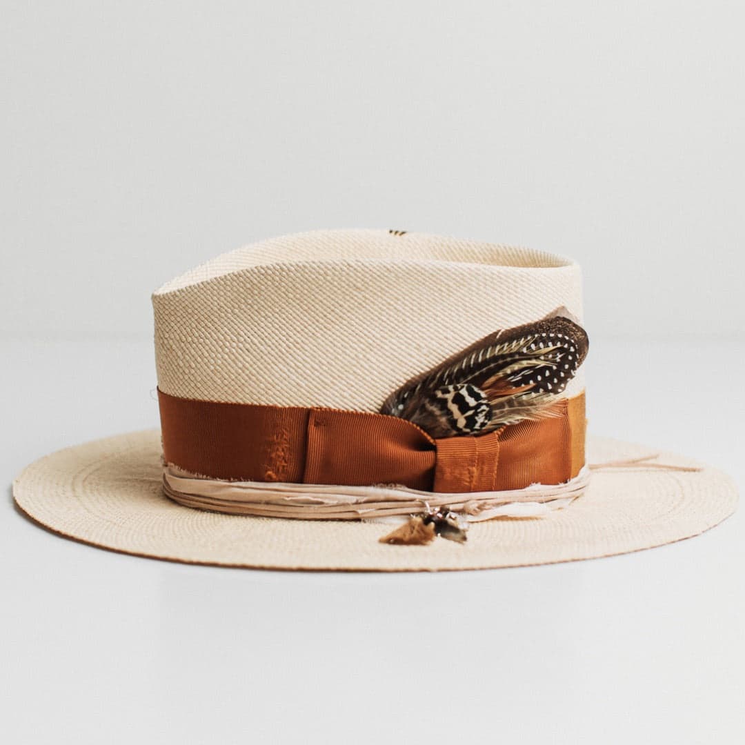 Left side view of the Roadie Panama natural straw hat by PHYLLi Designs with nude suede string and charm cluster with moonstone pendant.