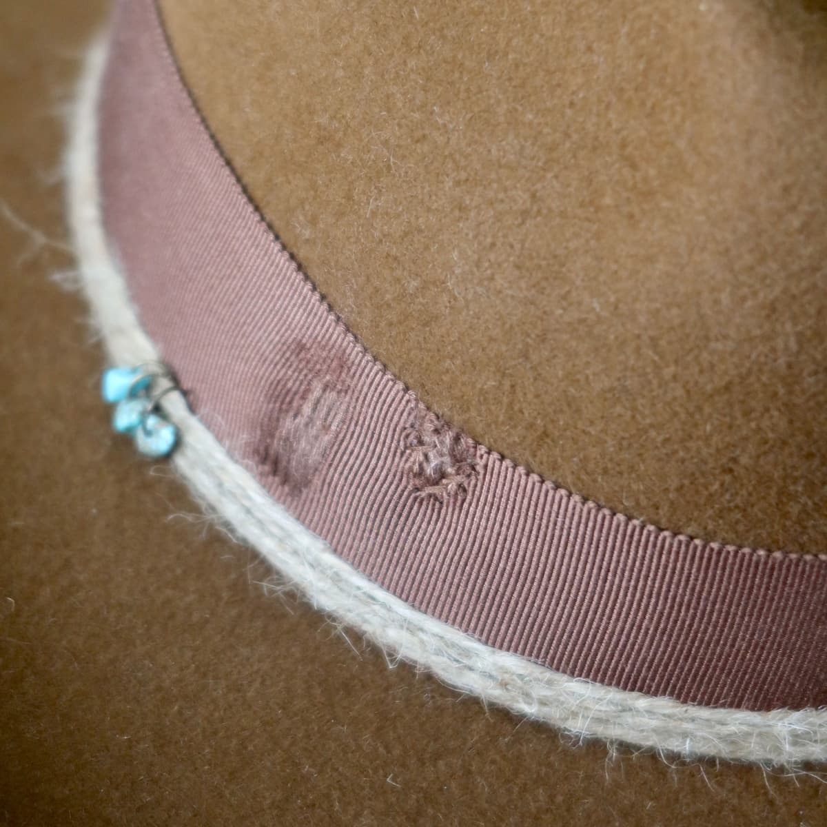 Close up detail of the Rue cowboy hat showing distressed chocolate darned patch stitching on the grosgrain band.