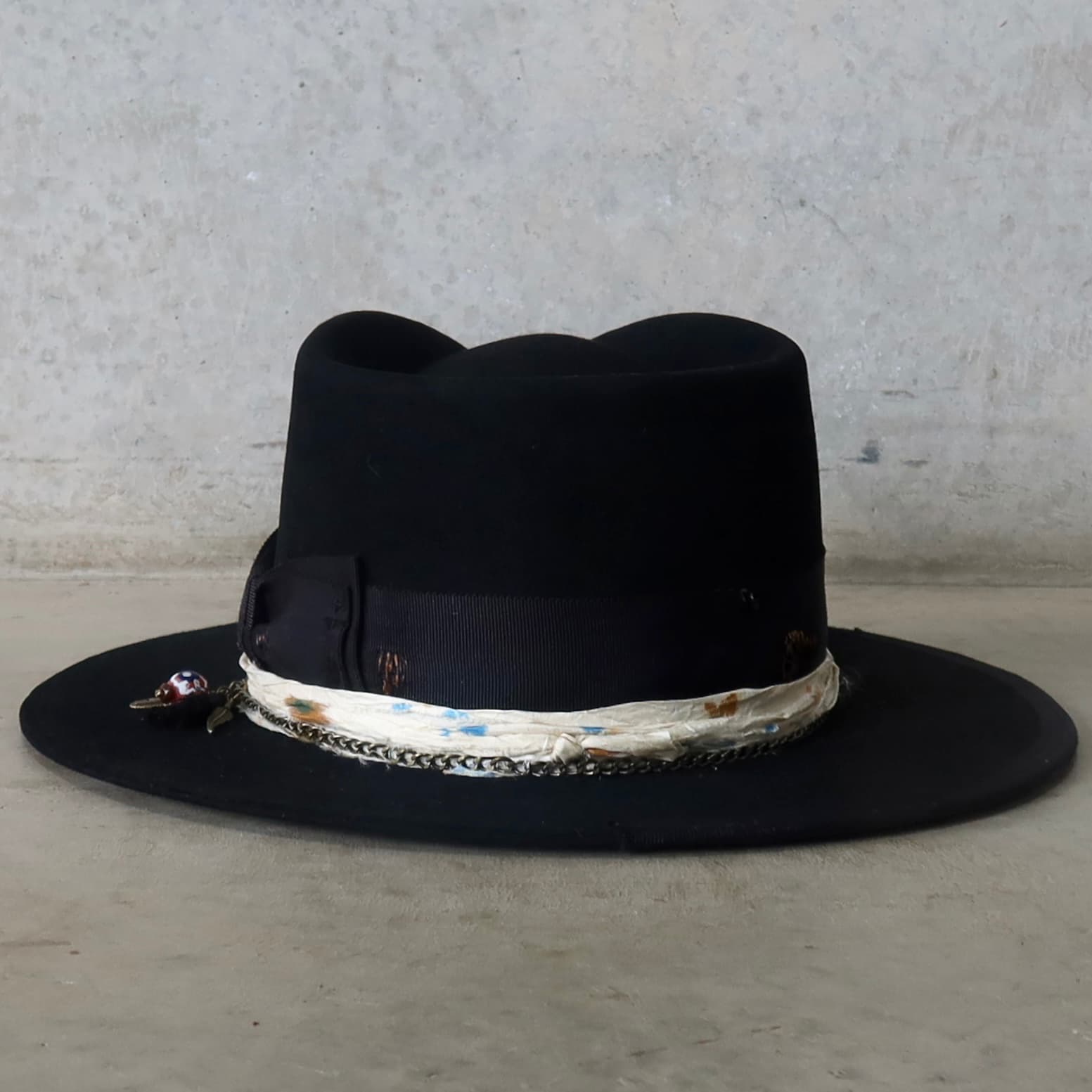 Back view of the black felt hat Saint by PHYLLi Designs featuring distressed grosgrain bow band and sari silk crown trim.