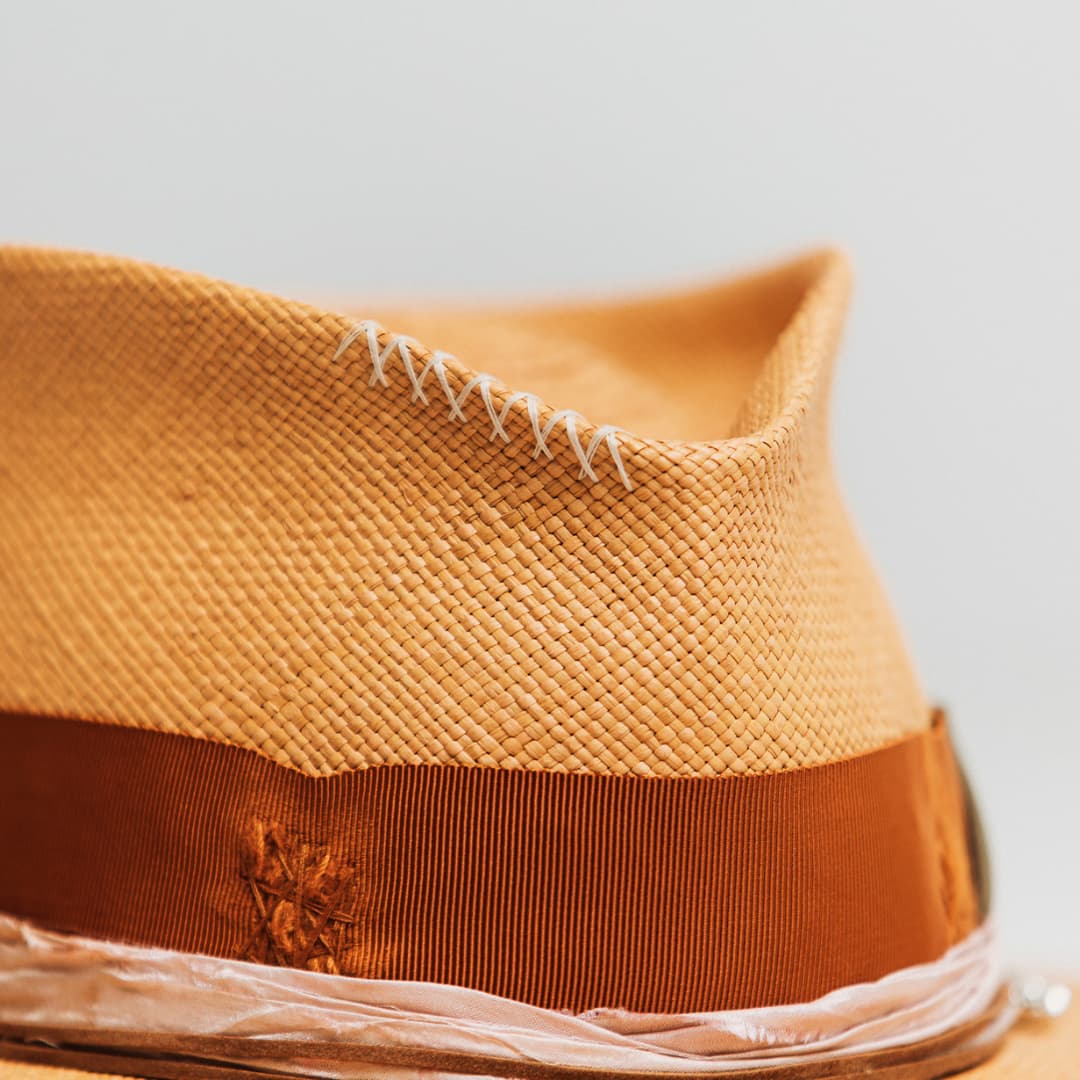 Detail of Santa Monica Panama showing hand stitching along the crown edge with distressed Rust grosgrain band and sari silk trim.