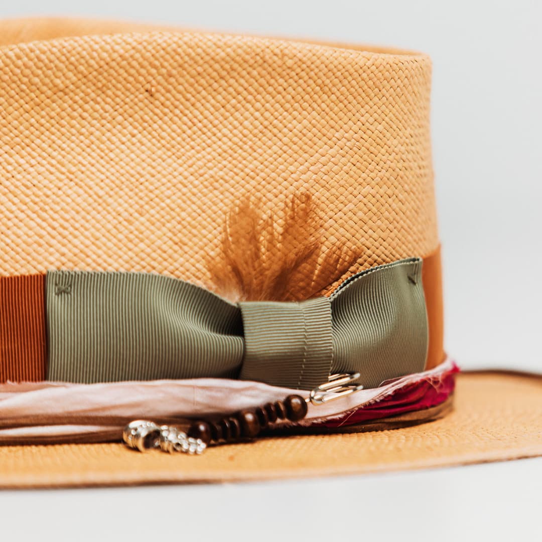 Detail of Santa Monica Panama showing Oil Green grosgrain bow, silver hat pin with wooden beads and pendant charms.