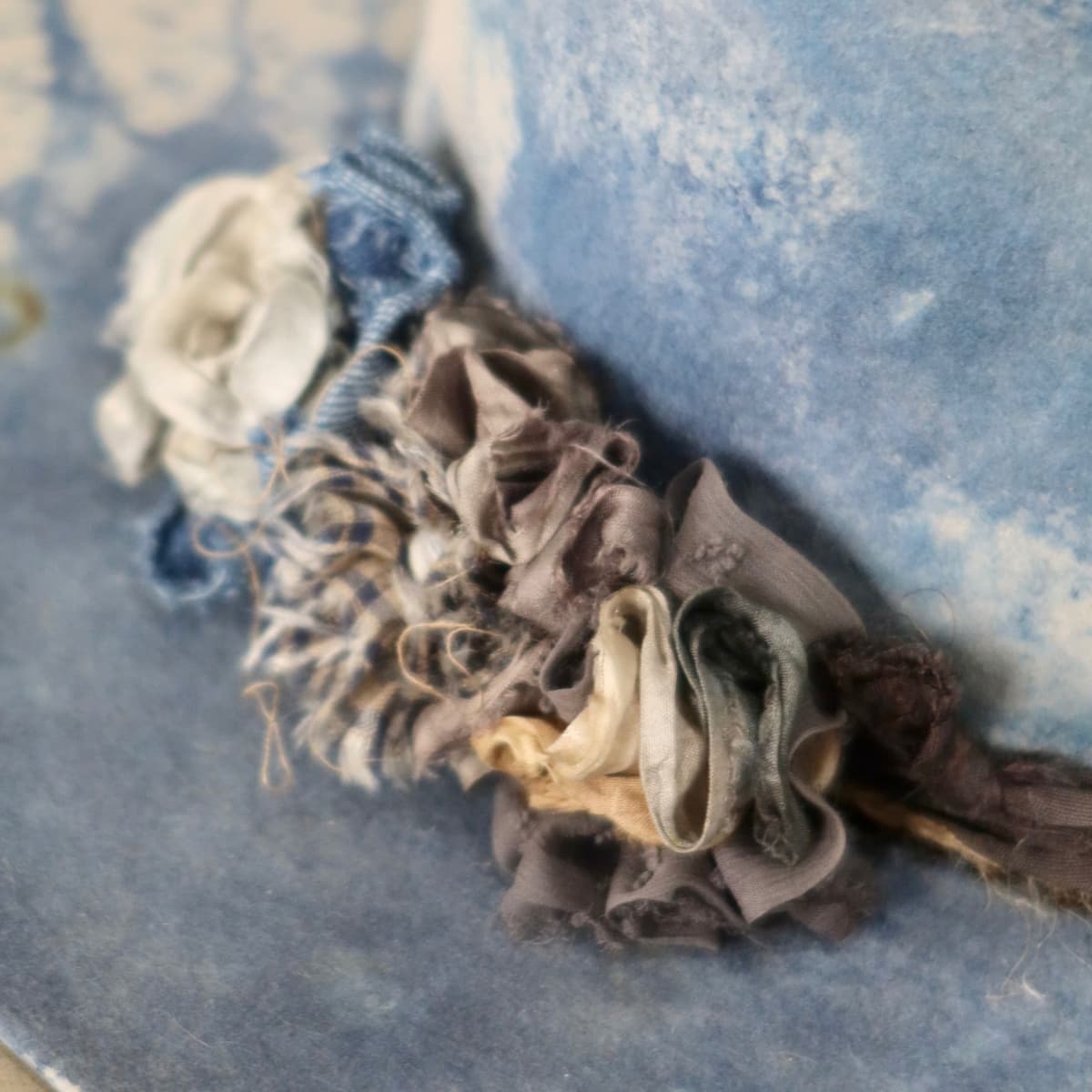 Close up detail of the Shibori Limited Edition felt hat showing layered sari silk lapel blooms in neutral tones with pearl accents.