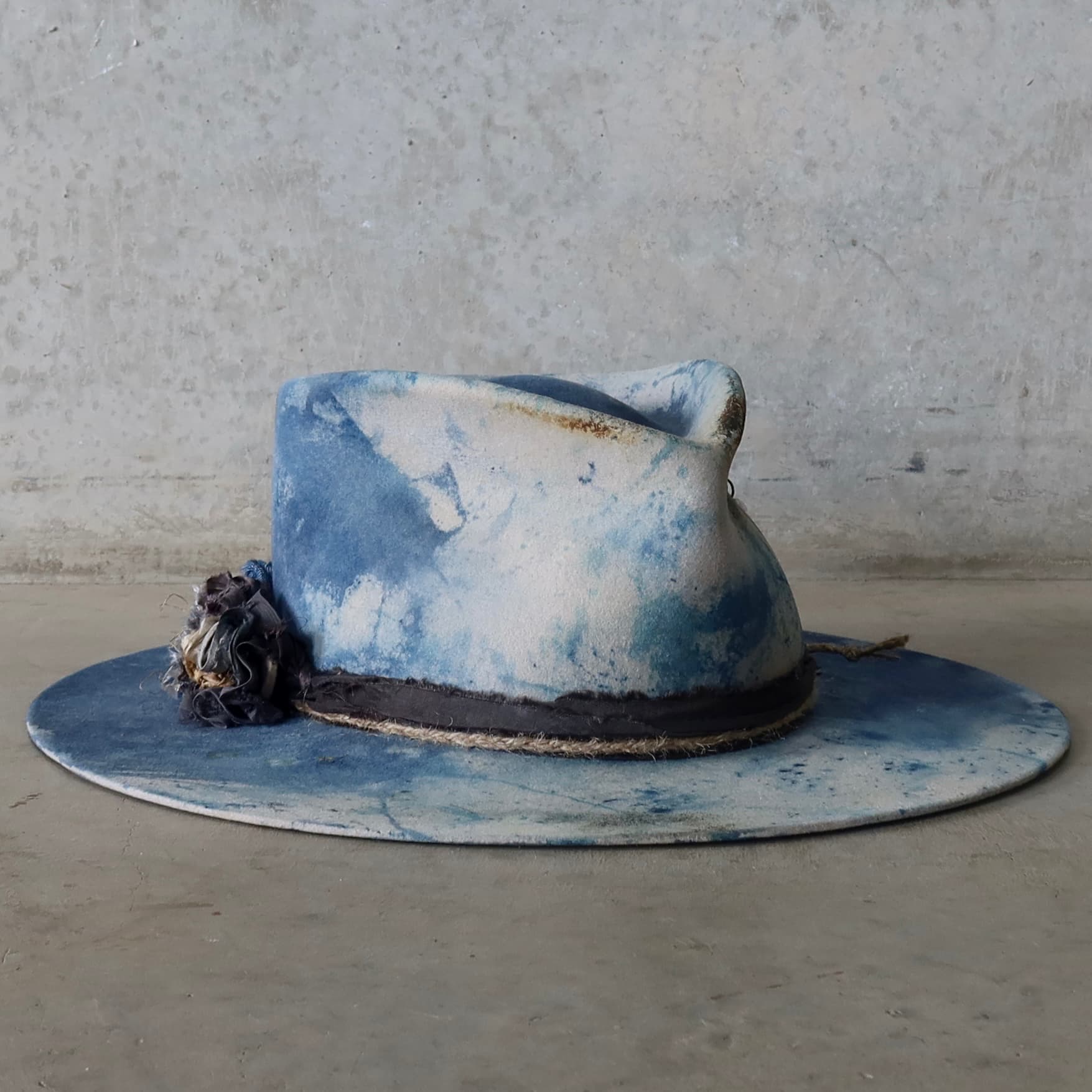 Front right angle of the dove grey indigo tie dye felt hat Shibori Limited Edition by PHYLLi Designs with lapel blooms and sari silk trim.