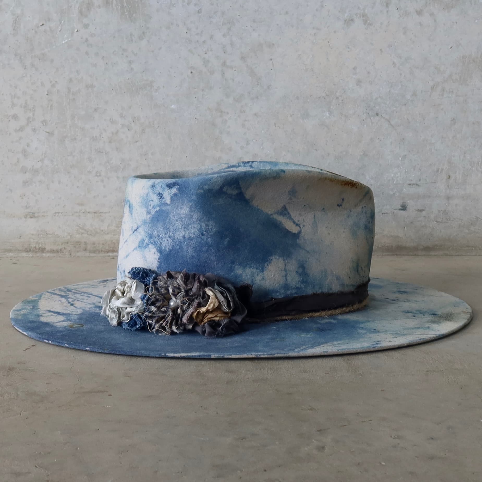 Right side view of the dove grey indigo tie dye felt hat Shibori Limited Edition by PHYLLi Designs with sari silk lapel blooms.