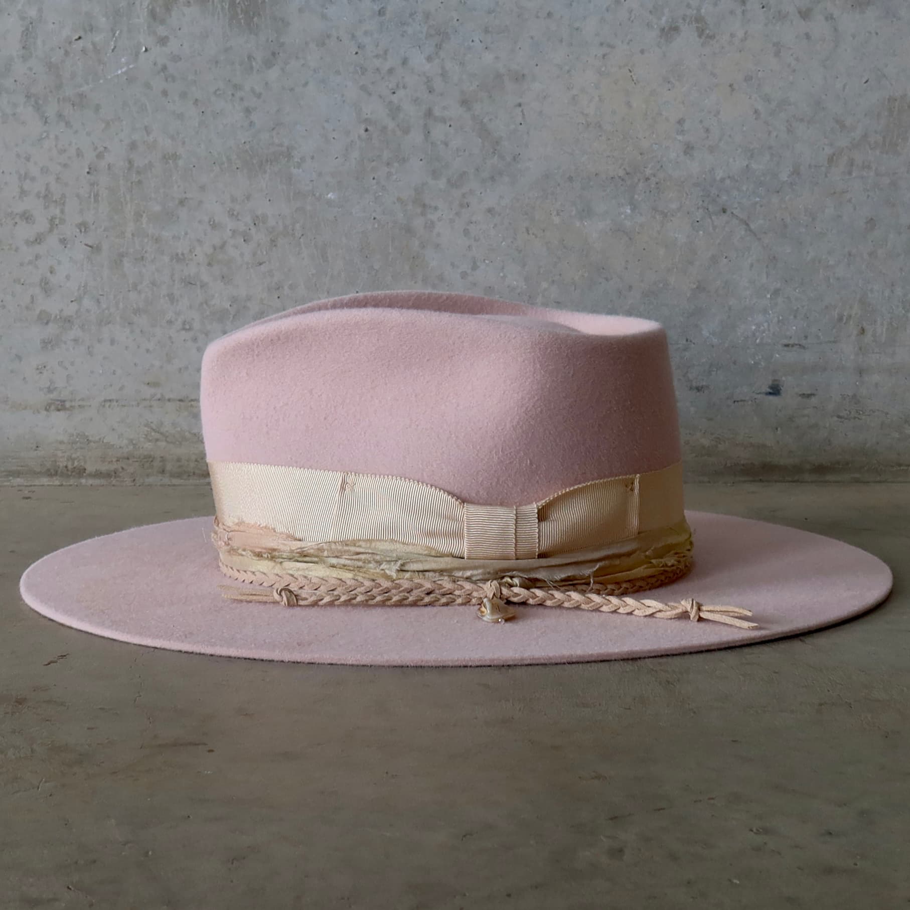 Left side view of the baby pink felt hat Sorbet by PHYLLi Designs with sorbet tie dye sari silk trim and plaited suede string.