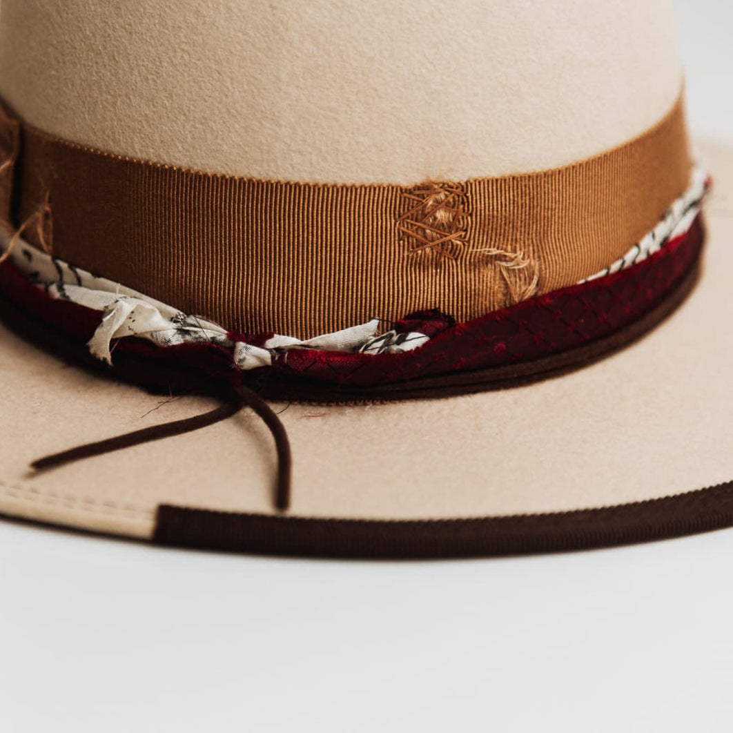 Close up detail of the Spice Alley felt hat showing crimson red sari silk trimming with black and white patterned fabric.