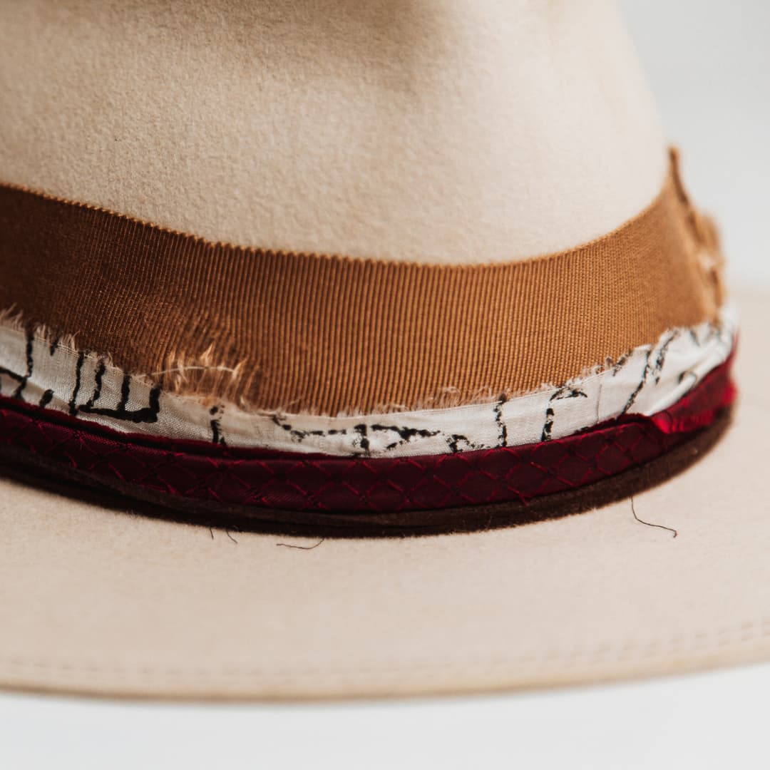 Close up detail of the Spice Alley felt hat showing distressed copper grosgrain band with copper darned patch stitching.