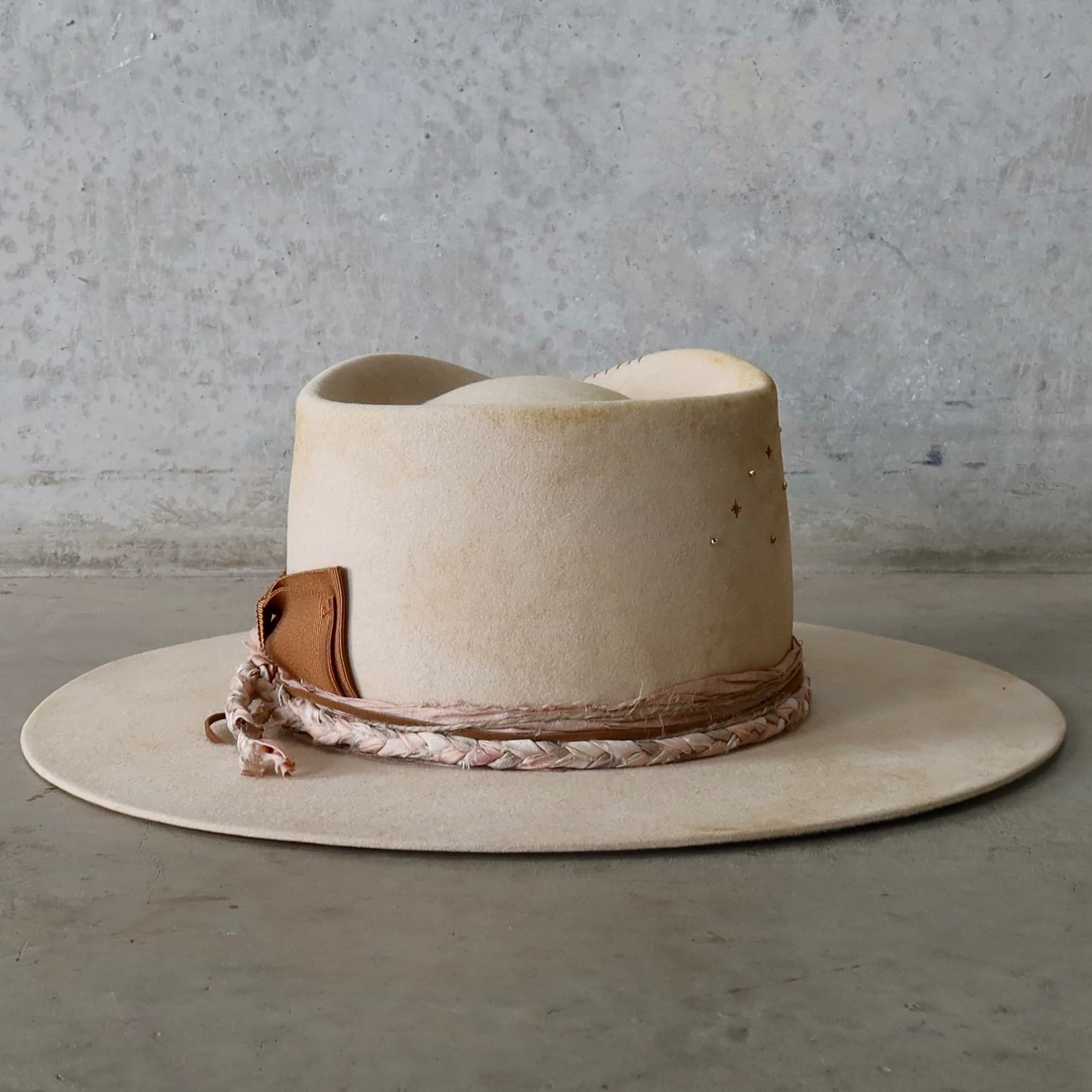 Back view of the beige distressed felt hat Starlight by PHYLLi Designs featuring copper twinkle star stitching with gold glass bead details.