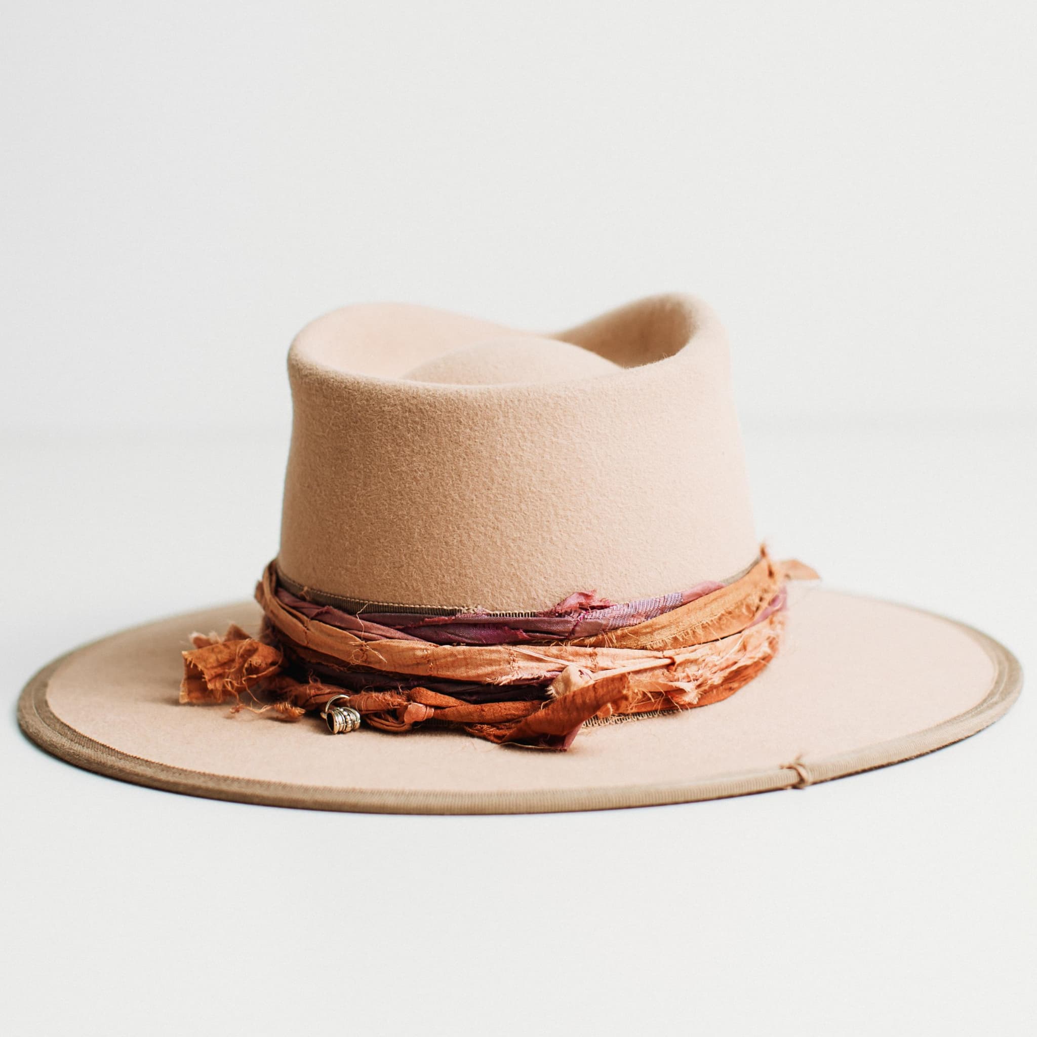 Back view of Sunset sand felt hat with layered sari silk band and pendant charm by PHYLLi Designs.