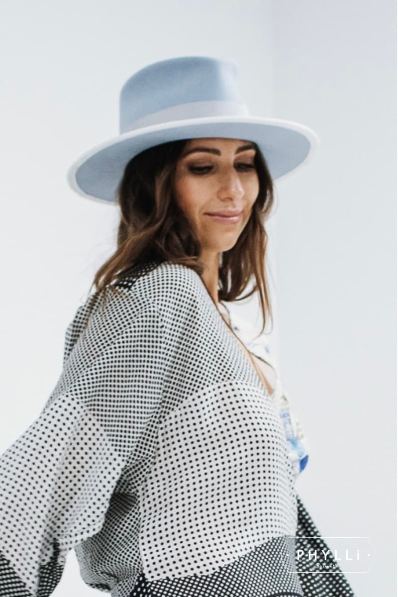 Woman wearing The Arrow crystal blue felt hat by PHYLLi Designs with dove grosgrain band, ivory velvet bow and dusty blue sari silk trim.