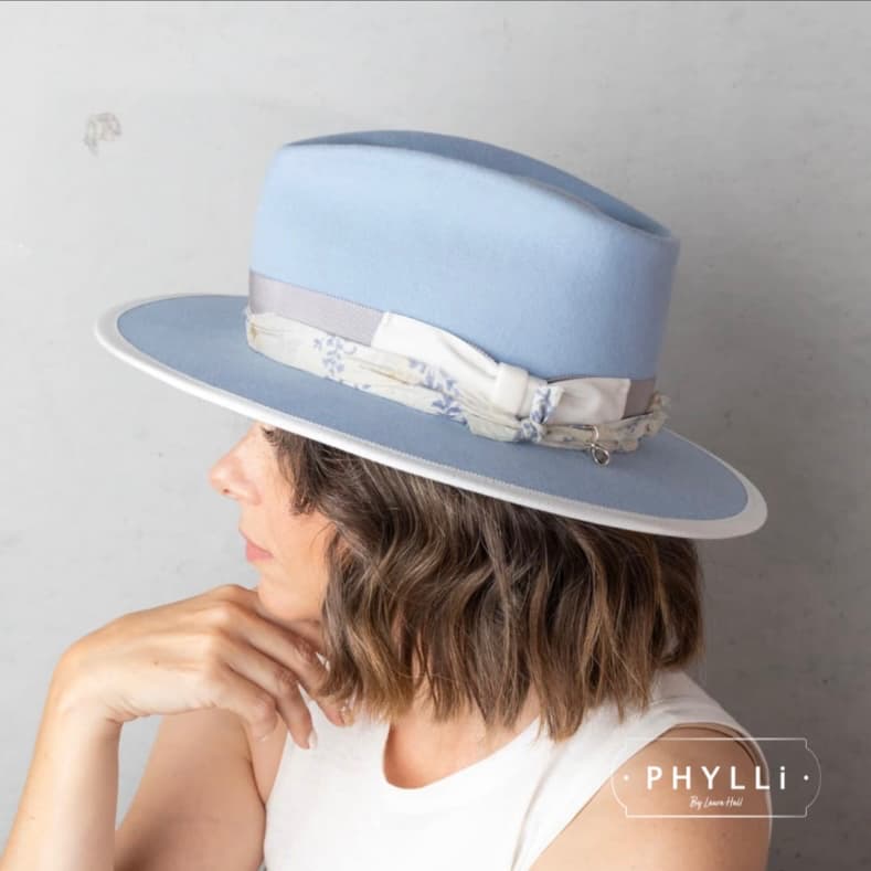 Woman wearing The Arrow crystal blue felt hat by PHYLLi Designs with dove grosgrain band, ivory velvet bow and dusty blue sari silk trim.
