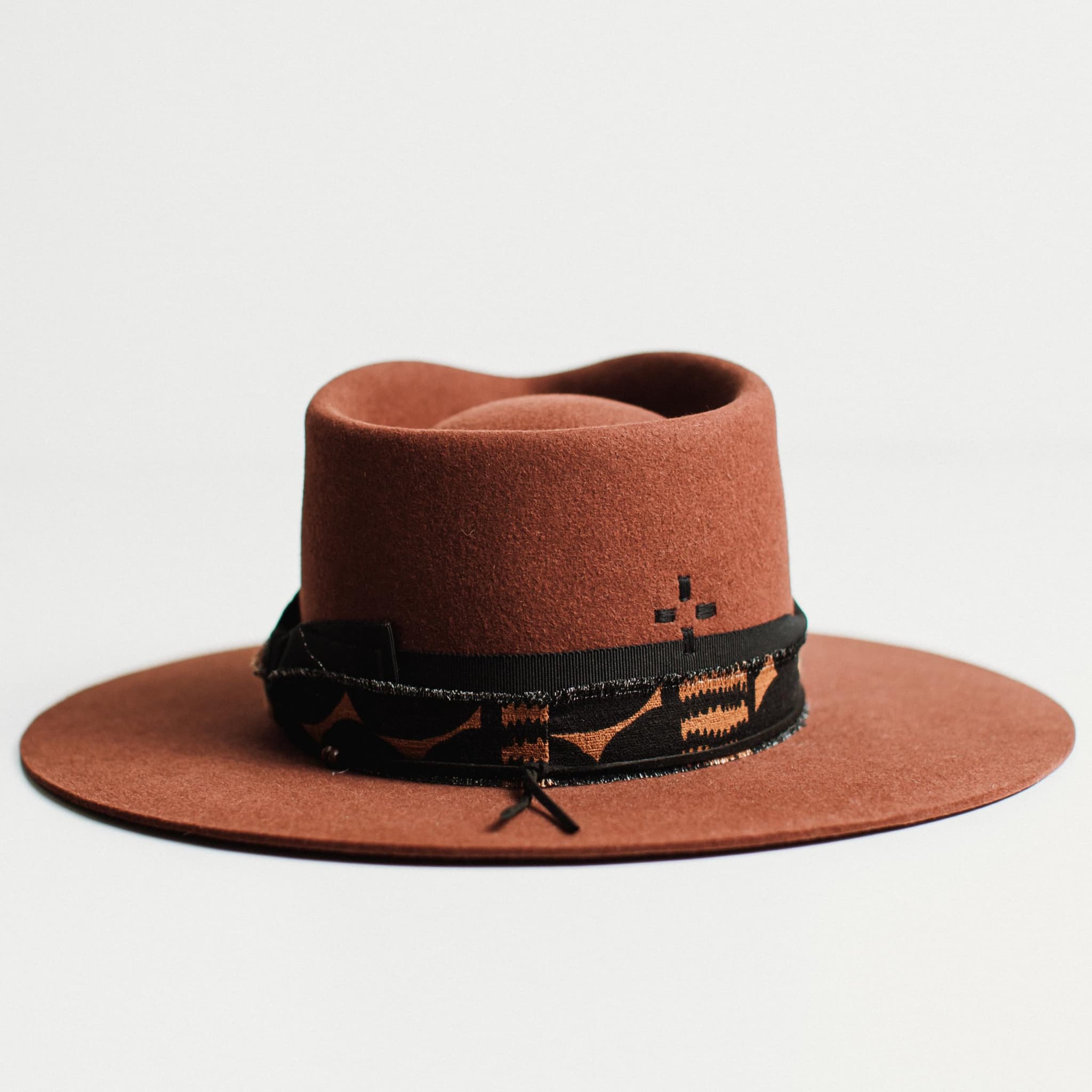 Back view of russet felt hat with decorative band by PHYLLi Designs on a light grey background.