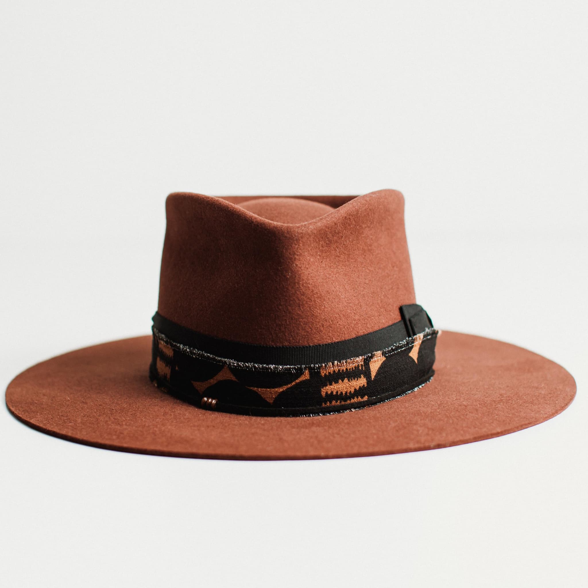 Front view of russet felt hat with decorative band by PHYLLi Designs on a light grey background.