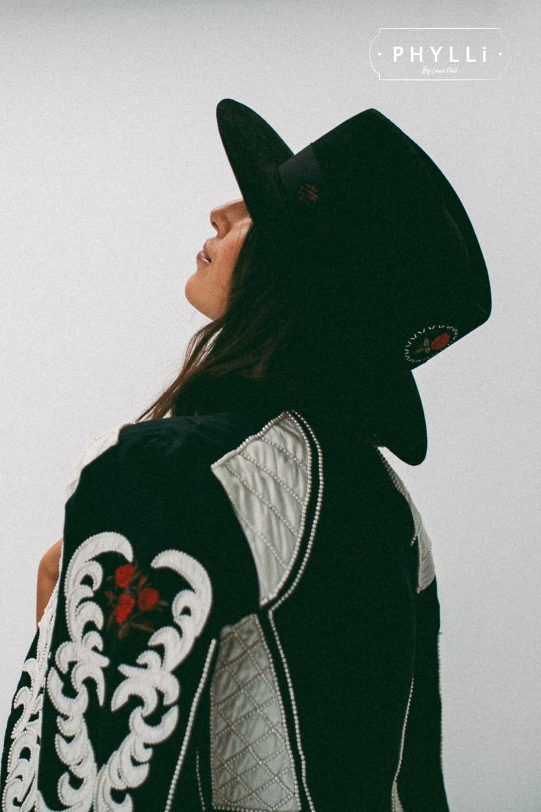 Fashion model wearing The Betty black felt hat by PHYLLi Designs styled with embroidered jacket.