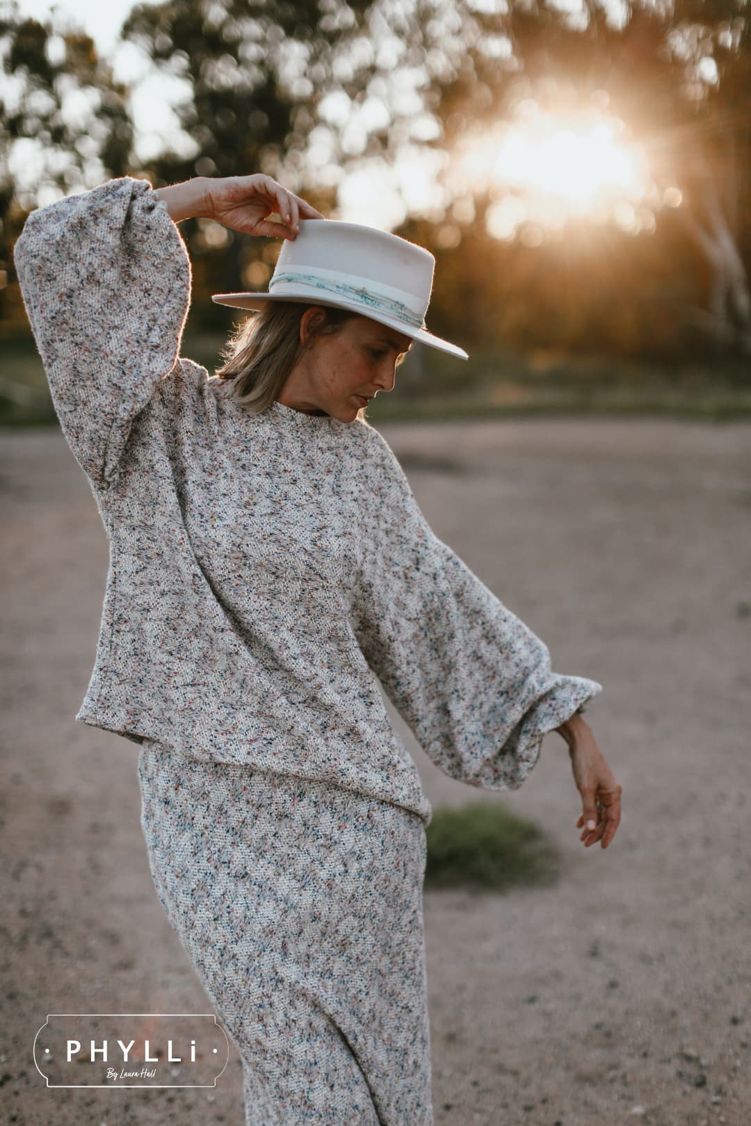 Grace Brennan wearing The Dove dove felt hat with blue and teal sari silk trim by PHYLLi Designs in golden hour outdoor setting.