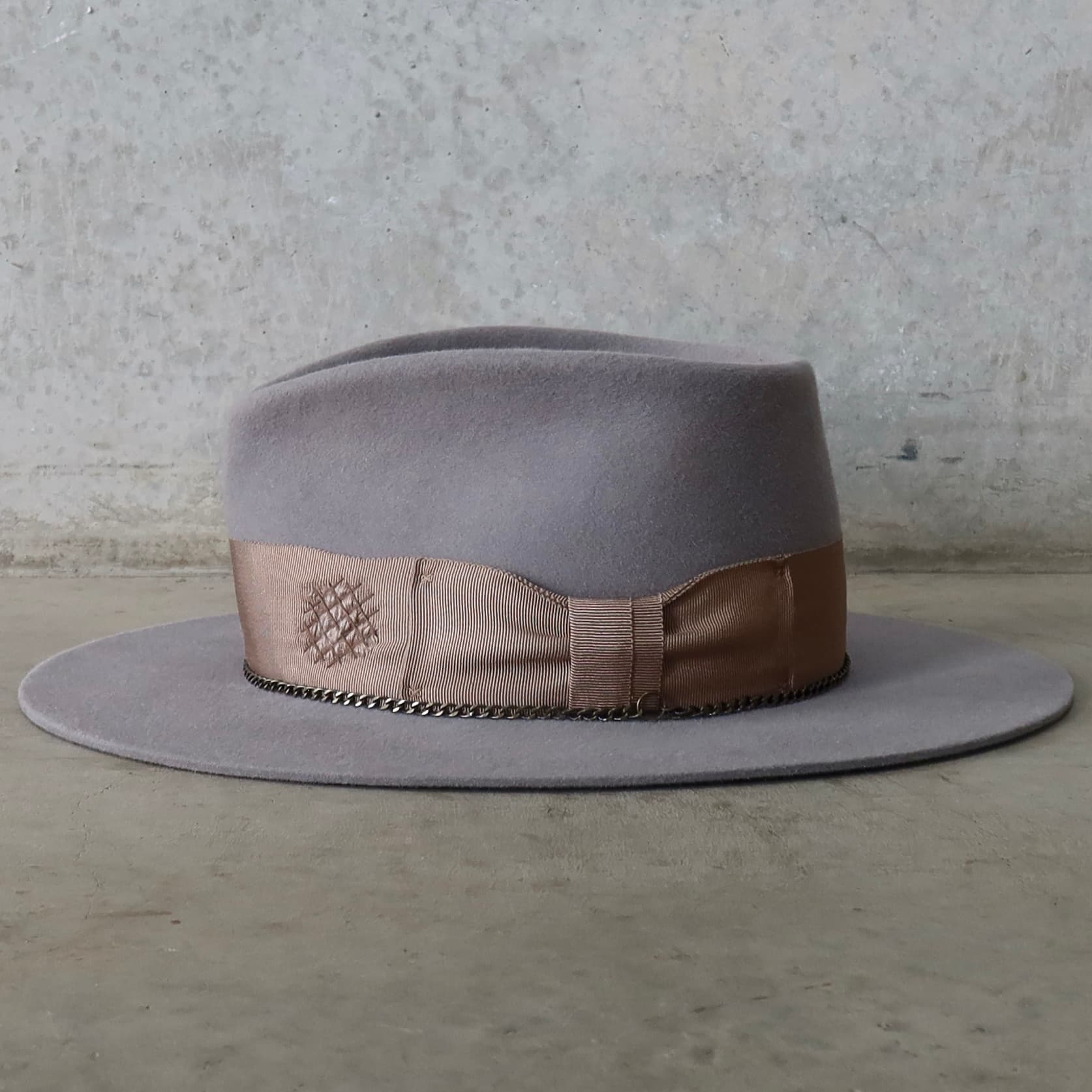 Left side view of Drifter taupe felt hat featuring distressed patches and bronze crown chain.