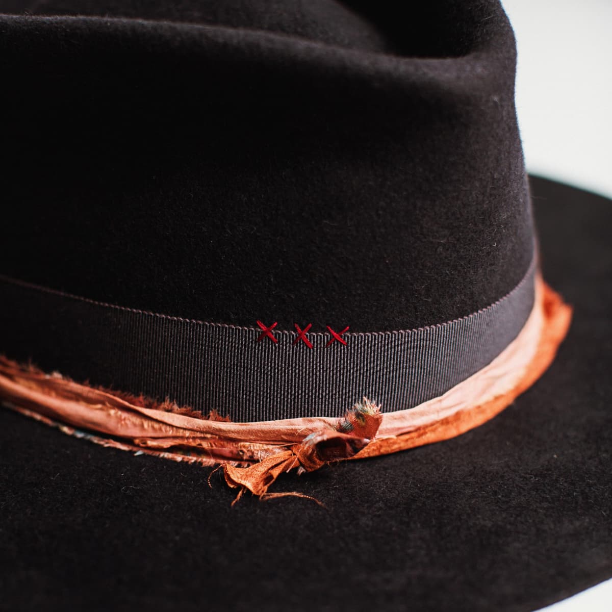 Close-up detail of dark navy felt hat showing decorative band and felt texture.