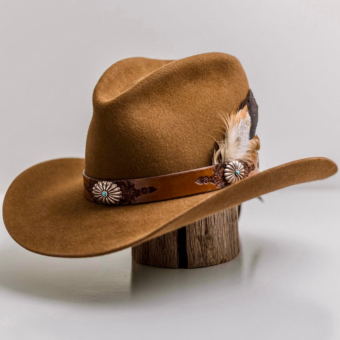 Front left angle of the Caramel cowboy hat The PHYLLi Caramel by PHYLLi Designs with Buffalo Girl Western floral tie back hat band and fallen feather bunch.