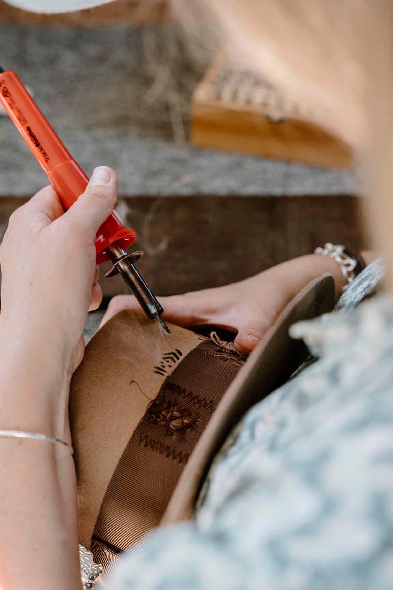 Personalised branding being burned into the back of a handcrafted felt hat by PHYLLi Designs.