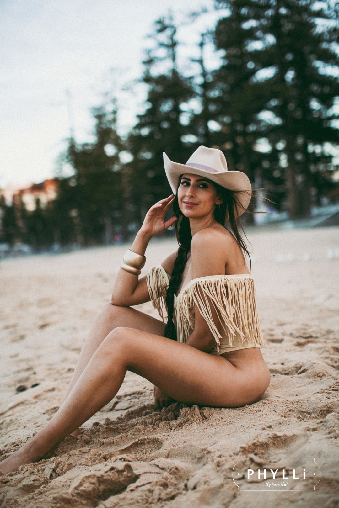 Woman wearing The Plains beige cowboy hat by PHYLLi Designs with plaster grosgrain bow band photographed at beach.