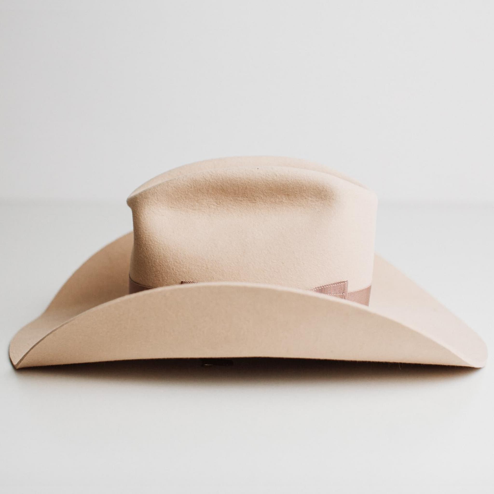 Left side view of The Plains beige felt cowboy hat by PHYLLi Designs with wide shaped brim and plaster grosgrain band.
