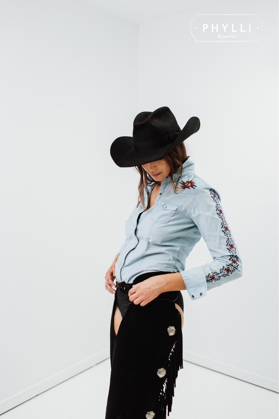 Studio model wearing The Plains black rabbit felt cowboy hat by PHYLLi Designs with wide shaped brim and open road crown.